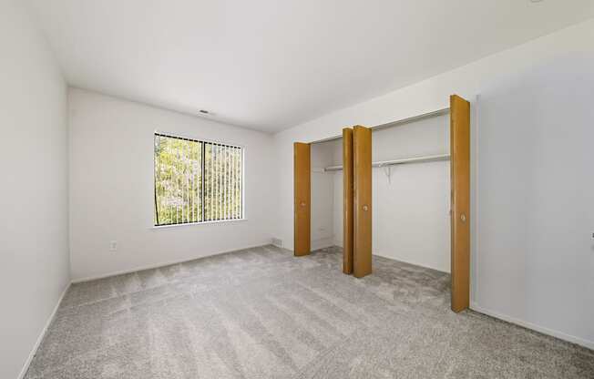 A room with a carpeted floor and a window with blinds.
