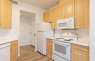 A kitchen with white appliances and wooden cabinets at Cornerstone at Gale Ranch Apartments, California