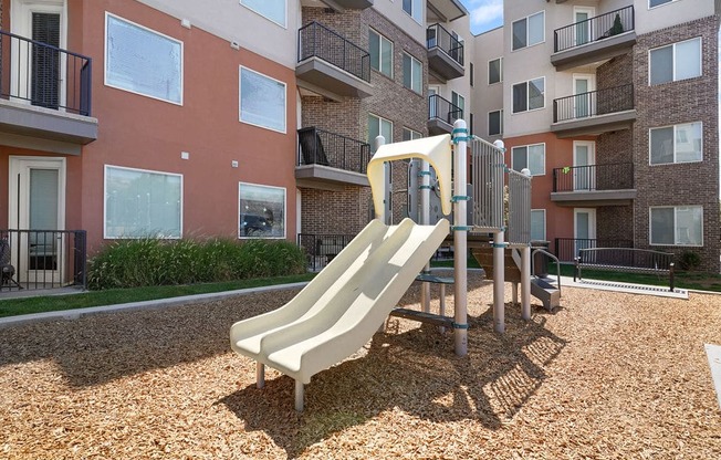 a playground with a slide in front of an apartment building