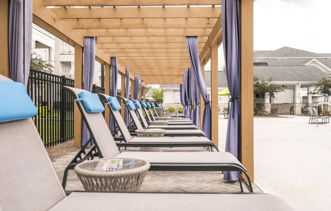 a row of lounge chairs on the porch of a building