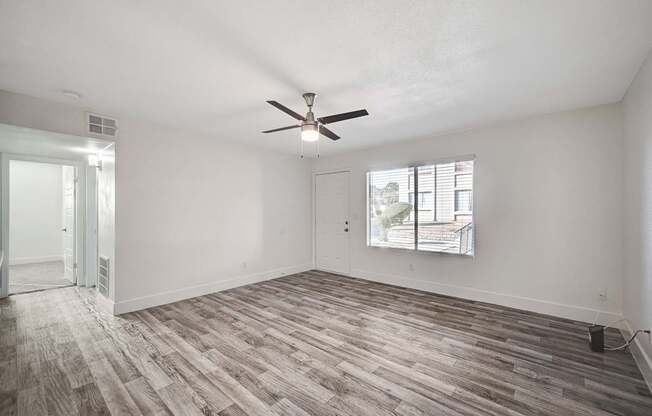 A room with a ceiling fan and a window with blinds.
