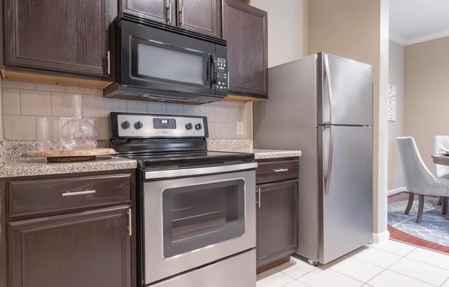 a kitchen with dark cabinets and stainless steel appliances