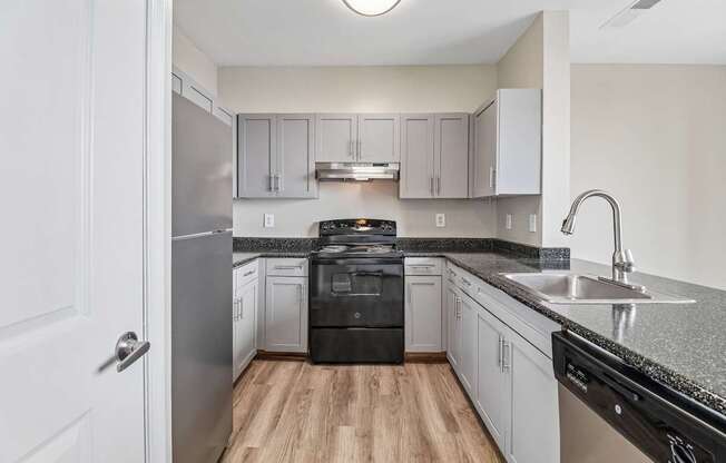A kitchen with a black dishwasher and stove top oven.