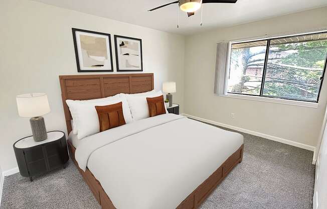 A bedroom with a large bed, two lamps, and two picture frames on the wall.
