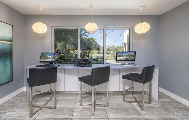 A modern home office with a large window and two desks.