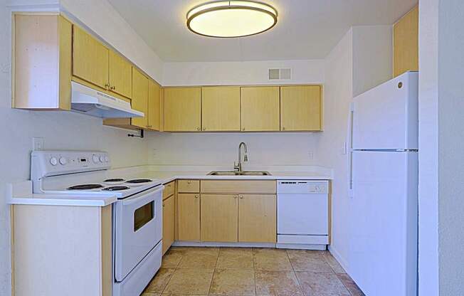 A kitchen with white appliances and wooden cabinets.