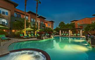 pool and hot tub at night, with lounge chairs surrounding