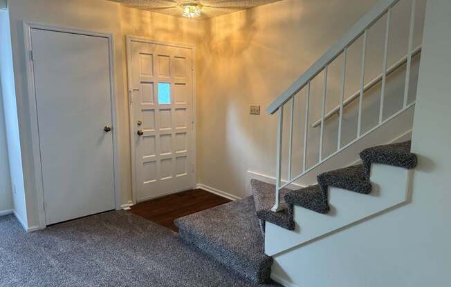 A hallway with a staircase and two doors.