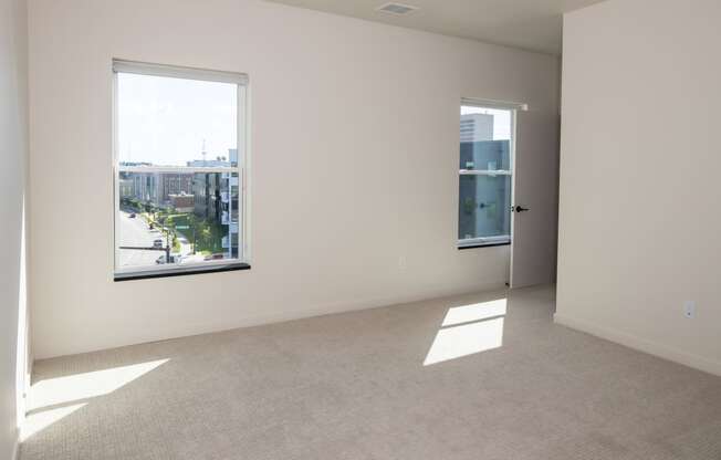 an empty living room with two windows and a city view at Riverhouse Apartments, Fargo, ND