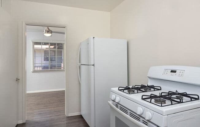 an empty kitchen with white appliances and a white refrigerator