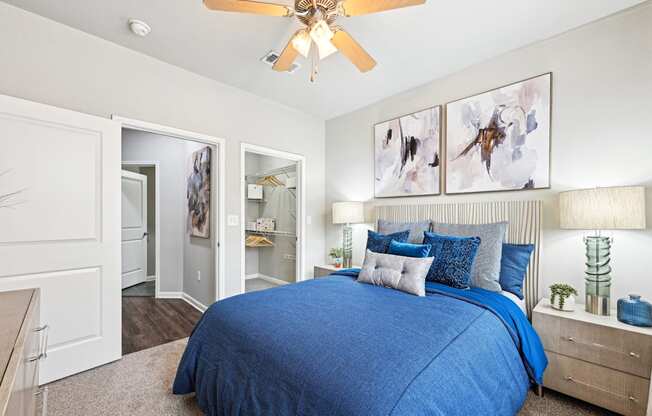 Comfortable bedroom with blue bedding and artistic wall decor at The Grand at Upper Kirby apartments in Houston, TX