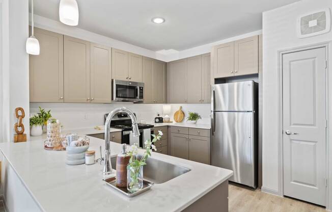 a white kitchen with stainless steel appliances and a sink