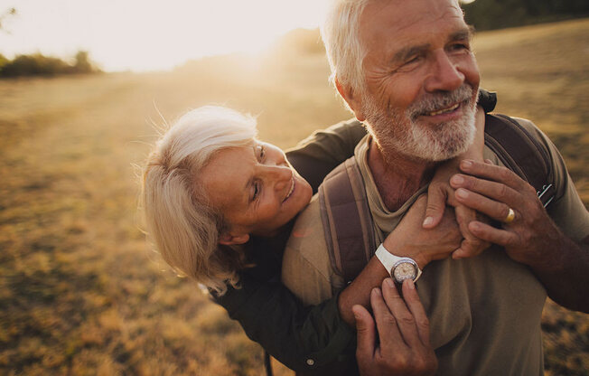 an older couple embraces in a field as the sun sets at Brownstones at Palisade Park Townhomes, Colorado, 80023
