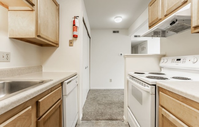 an empty kitchen with white appliances and wood cabinets