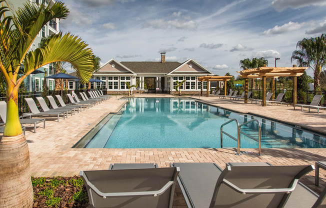 a swimming pool with chairs and a house in the background