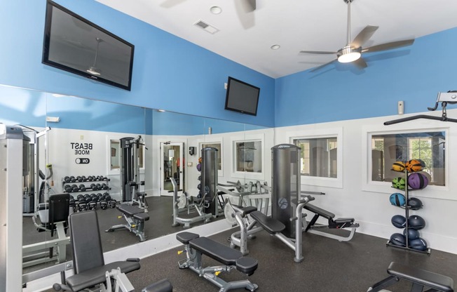 a gym with weights and cardio equipment and a tv