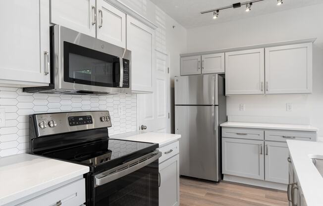 a kitchen with white cabinets and stainless steel appliances