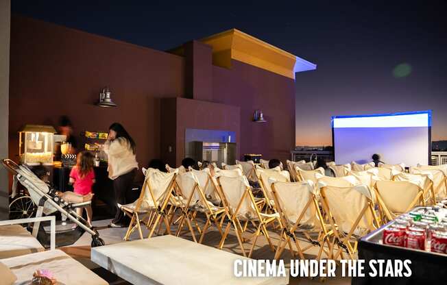 A group of people are sitting in chairs outside watching a movie under the stars.