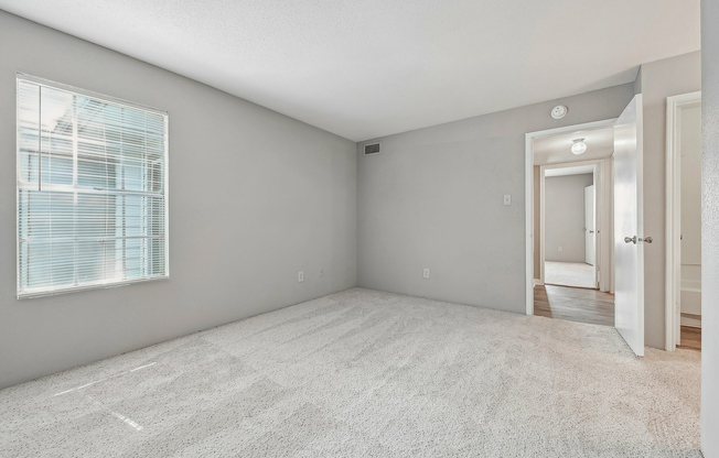 Bedroom with soft carpeting and large window at Driscoll Place Apartments.