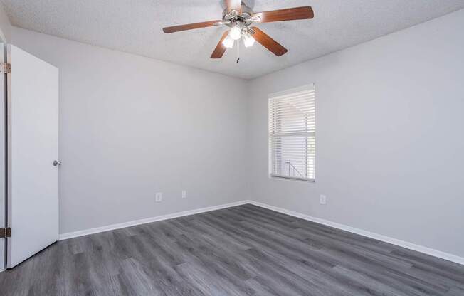 A room with a ceiling fan and a window with blinds.
