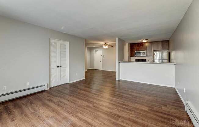 an empty living room and kitchen with wood flooring