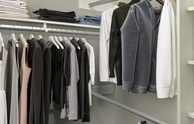 a walk in closet with a rack of clothes hanging on it