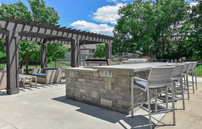 a patio with a stone bar and chairs and a pergola