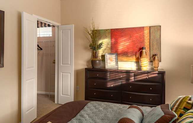 a bedroom with a large bed and a dresser with a plant on top of it