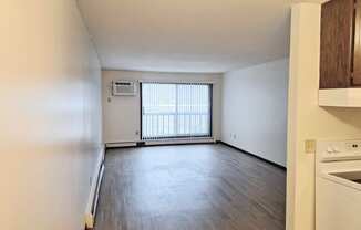 an empty kitchen and living room with wood flooring and a window