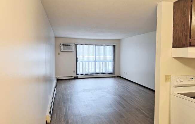 an empty kitchen and living room with wood flooring and a window