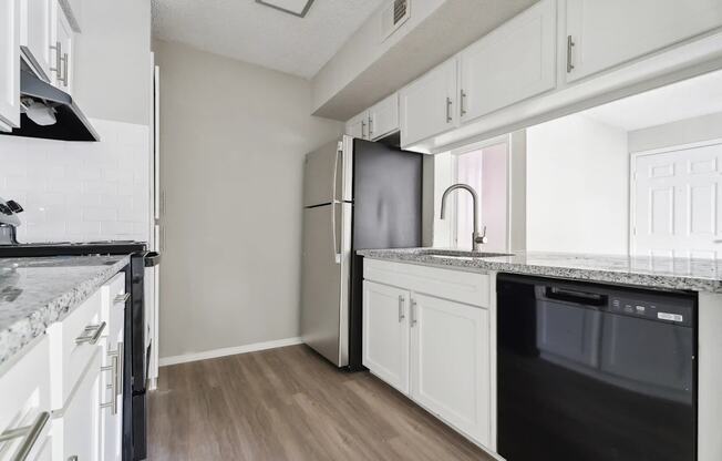 A kitchen with white cabinets and a black fridge.