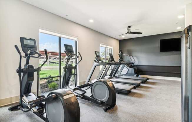 the gathering atrium gym with cardio equipment and a tv