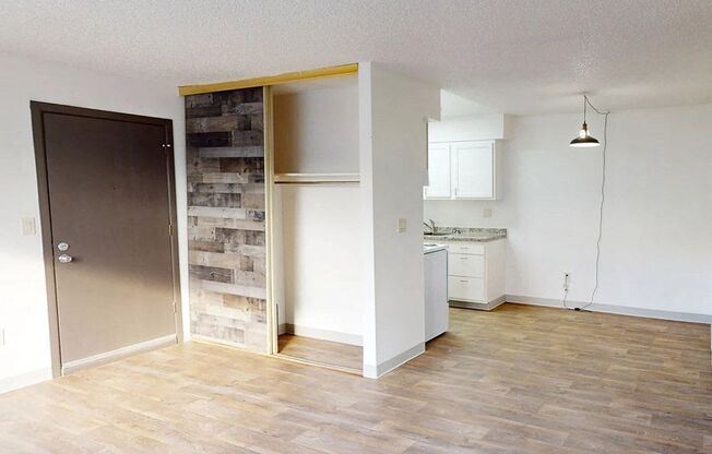 an empty living room and kitchen with a wood floor