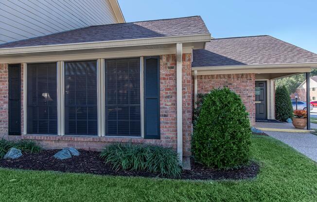 a house with a lawn in front of a brick building