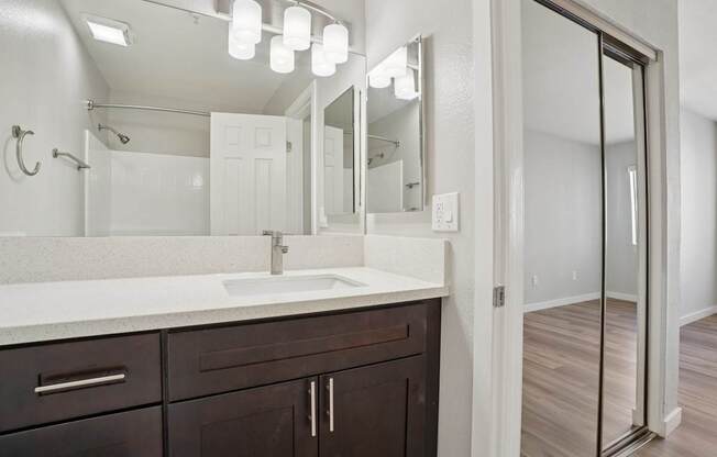 A bathroom with a sink, mirror, and wooden floor.