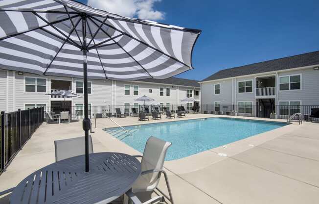 our apartments have a large pool and patio with chairs and an umbrella