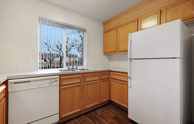 A kitchen with a white fridge, dishwasher and wooden cabinets.