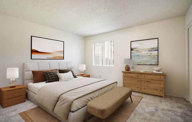 A bedroom with a large bed, a bench, and two framed pictures on the wall.