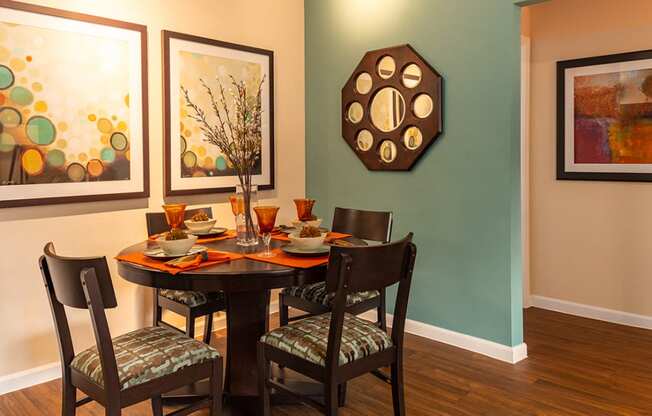 a dining room with a table and chairs and paintings on the wall