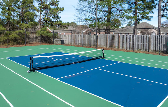 A tennis court with a net and a green and blue surface.