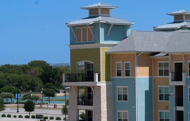 a large apartment building with two balconies and a large body of water in the background