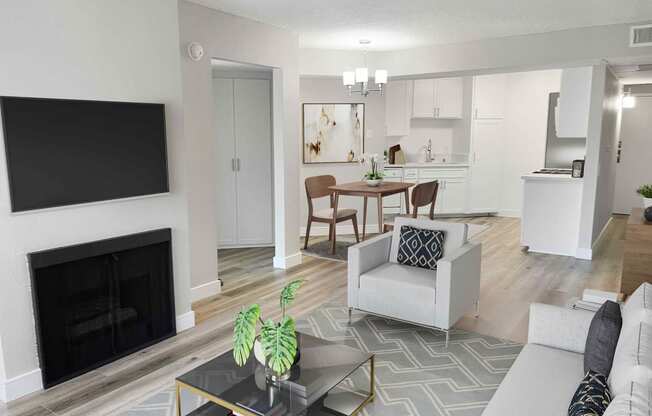 a living room with a fireplace and a kitchen in the background