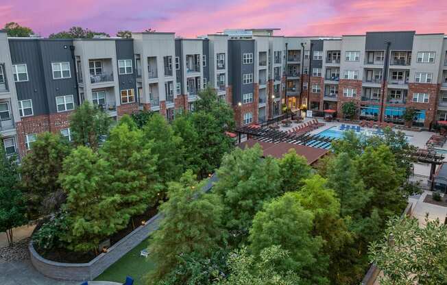 an aerial view of an apartment complex with a pool and trees