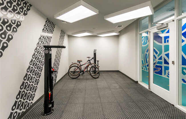 A bicycle is parked in a hallway with a black and white patterned wall and a glass door.