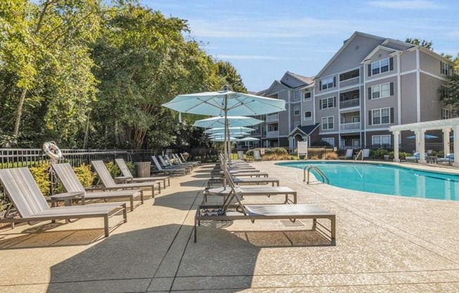 a pool with chairs and umbrellas in front of a building at Marina Point, Chattanooga