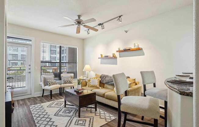 A living room with a couch, chairs, and a rug.