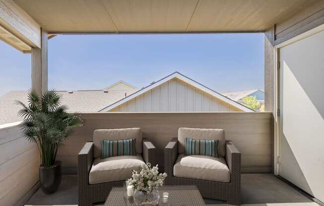 a covered patio with two chairs and a palm tree