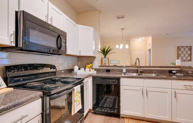 a kitchen with white cabinets and black appliances