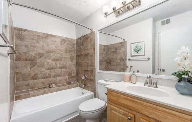 A bathroom with a white tub, sink, and toilet.