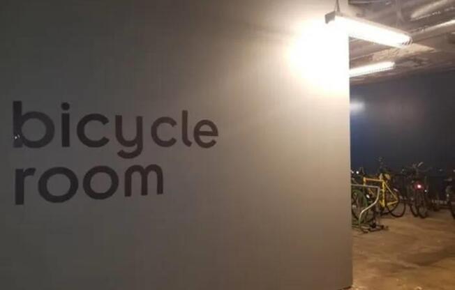 A bicycle room sign is illuminated by a light.